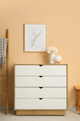 Chest of drawers with vase of white peonies and painting near beige wall