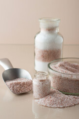 Himalayan pink salt and white rock salt in glass containers and jars with a metal spatula on a...