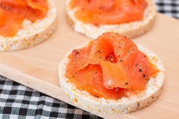 Tasty Rice Cake Sandwiches with Fresh Salmon Slices on Cutting Board - Close-Up. Easy Breakfast and...