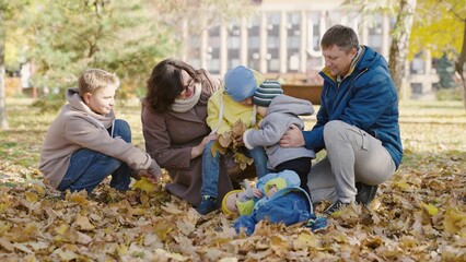 Big happy family, parents and children walk in park in autumn. Dad son, mom children play together on yellow leaves of city autumn park. Family vacation, weekend. Family walk with children outdoors