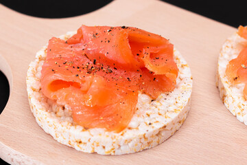 Tasty Rice Cake Sandwiches with Fresh Salmon Slices on Cutting Board - Close-Up. Easy Breakfast and Diet Food. Crispbread with Red Fish. Healthy Dietary Snack