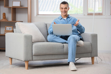 Young man with laptop video chatting at home