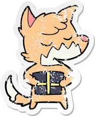 distressed sticker of a friendly cartoon fox with christmas present