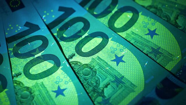 Euro banknotes under ultraviolet light. Security signs and elements on real 100 euro banknotes glow under UV light. Checking banknotes for authenticity. Protection against counterfeiters