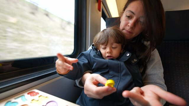 Mother teaching son to count while traveling by train commute. Attentive parent homeschooling her child, childhood education concept