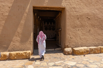 Arab man back view wearing traditional arab clothes wlaking next to Al Masmak Palace Museum in...