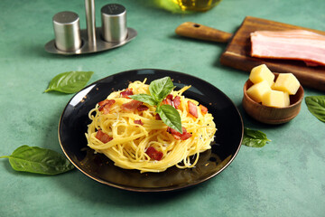 Plate with tasty pasta carbonara on green background