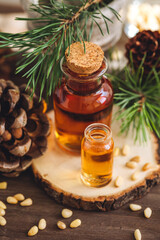 Organic essential oil, pine nuts, cedar cone on rustic wooden dark background. Concept of natural ingredients, naturopathy, herbal extracts and essence. Alternative medicine, aromatherapy