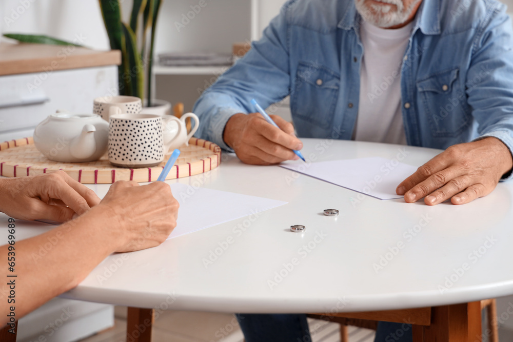 Sticker Mature couple signing divorce decree in kitchen, closeup