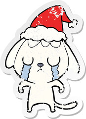 cute hand drawn distressed sticker cartoon of a dog crying wearing santa hat