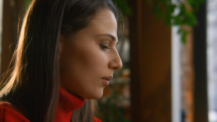 Woman showing emotions typing on laptop. Stock footage. Close-up of face of beautiful young woman in cafe. Beautiful woman is typing letter on laptop