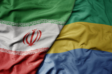 big waving realistic national colorful flag of iran and national flag of gabon .