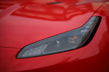 Close-up of the headlight of a red sports car.
