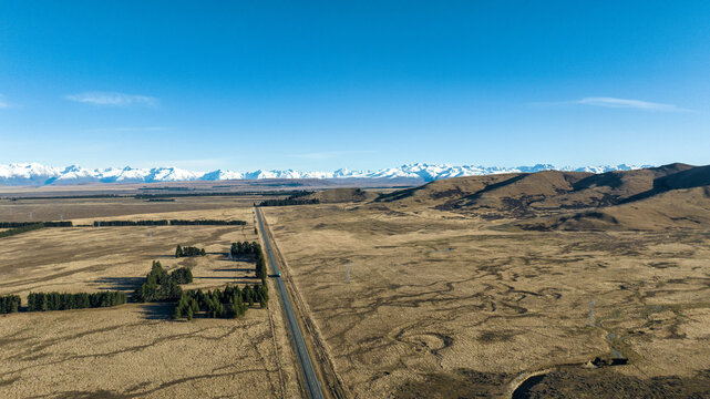 Long straight highway through farmland mto Lake Tekapo