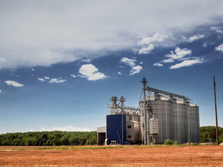 Modern silo or elevator for grain collection and storage by a wheat field. Agriculture industry and...