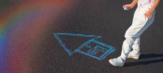 Widescreen photo of children's feet standing next to a house drawn with blue chalk on the asphalt