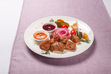 chicken kebab on a white plate with sauce and vegetables