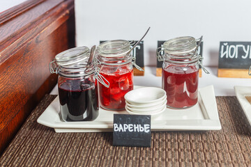 Jars of berry jam on the table in a restaurant.