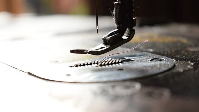Close up an antique sewing machine and needle working without threads on table wood