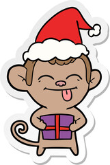funny hand drawn sticker cartoon of a monkey with christmas present wearing santa hat