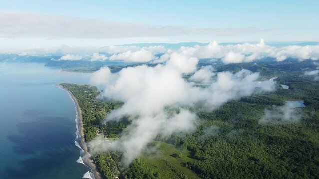 Aerial shot of the Costa Rican coastline with blue sky and scattered clouds. Zancudo village in Puntarenas province near Golfo Dulce is visible.