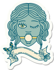 tattoo style sticker with banner of a winking female face wearing ball gag