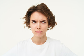 Close up of brunette woman shows angry face, frowning grumpy, pouting and looking disappointed,...