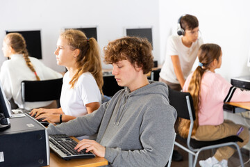 Pupils using computers at lesson, teacher teaching them in classroom