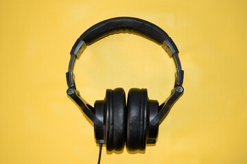 top view black headphone with cable on yellow background