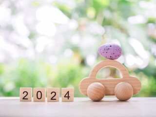 Wooden block with number 2024, Wooden toy car with Easter eggs for EASTER DAY concept.