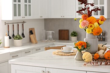 Beautiful autumn bouquets and pumpkins on marble table in kitchen