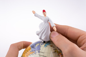 Hand holding a Derviş on a globe
