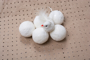 Artificial feather bird with white balls beside