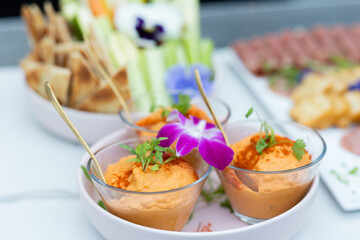 red pepper hummus served in glass dishes garnished with hibiscus flower, Ready to serve on bar with...