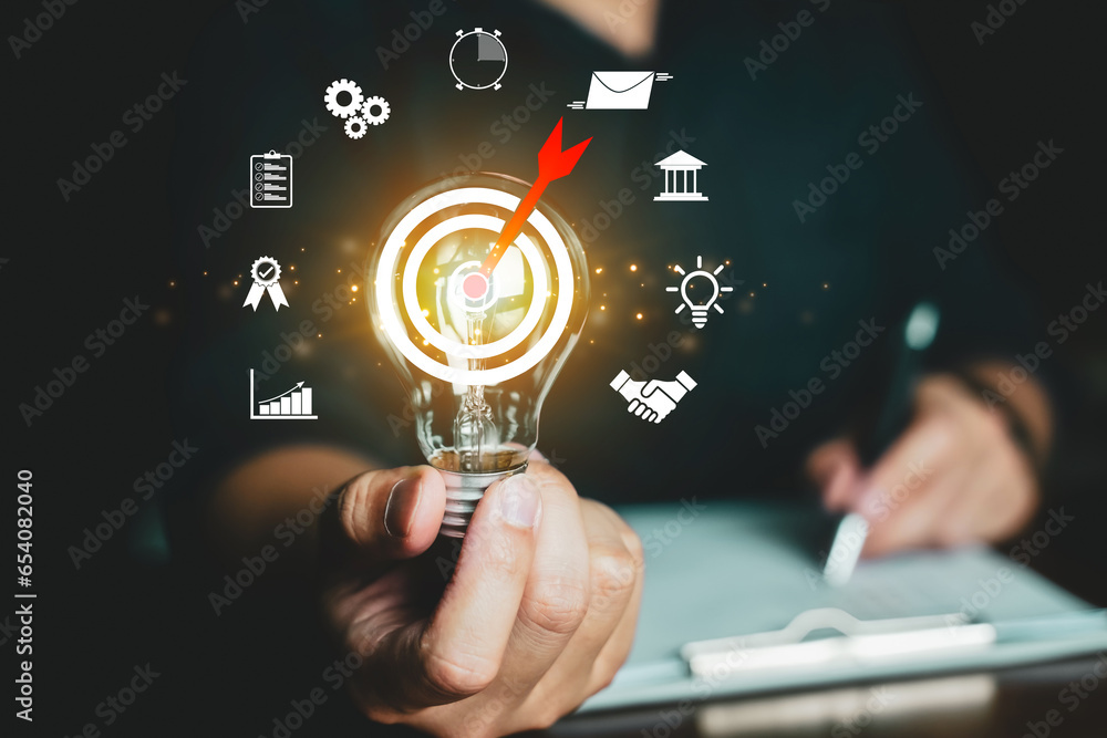Poster businessman holding glowing lightbulb with business objective target and goal concept , technology a