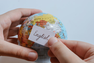 Hand holding notepaper with English wording on globe
