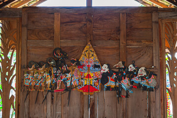 Wayang Kulit is displayed on a wooden wall. Indonesian and Javanese traditional shadow puppets made...