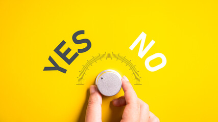 Hand adjusting the volume selector for choosing YES or NO on isolated yellow background....