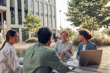 Smiling colleagues working together developing business strategy for project on office terrace