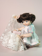 Vintage biscuit-porcelain doll girl plays with a baby doll in a cradle decorated with lace.  - 654103068