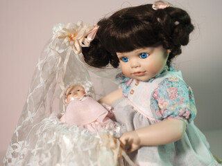Vintage biscuit-porcelain doll girl plays with a baby doll in a cradle decorated with lace.  - 654103212