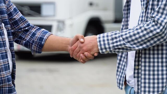 Two Truck Drivers Shaking Hands On Truck Parking, Close Up