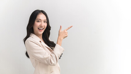 Portrait photo of young lively active Asian woman pointing at empty copy space can use for product advertising and marketing message for customer. Studio shot on white background.
