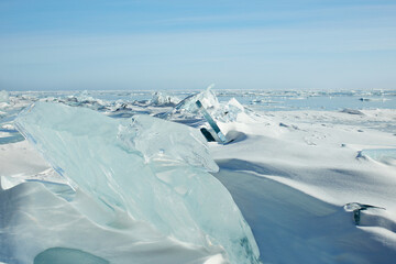Winter landscape. Huge blocks of transparent blue ice, ice floes on a frozen lake.