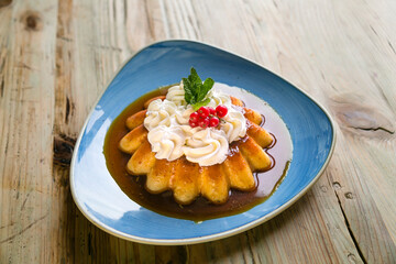 Gourmet egg custard dessert with whipped cream on top on a wooden table.