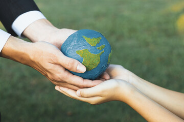 Businessman hand giving Earth globe to little boy as Earth day concept as corporate social...