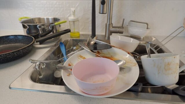 pile of dirty dishes in the kitchen sink, washing kitchenware at home