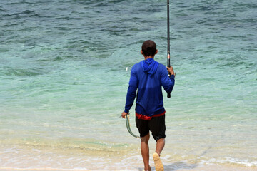 A man walks on a beach with beautiful white sand for fishing