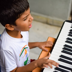 Asian boy playing the synthesizer or piano. Cute little kid learning how to play piano. Child's...