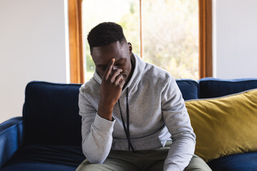 Sad african american man sitting on sofa having video call at home